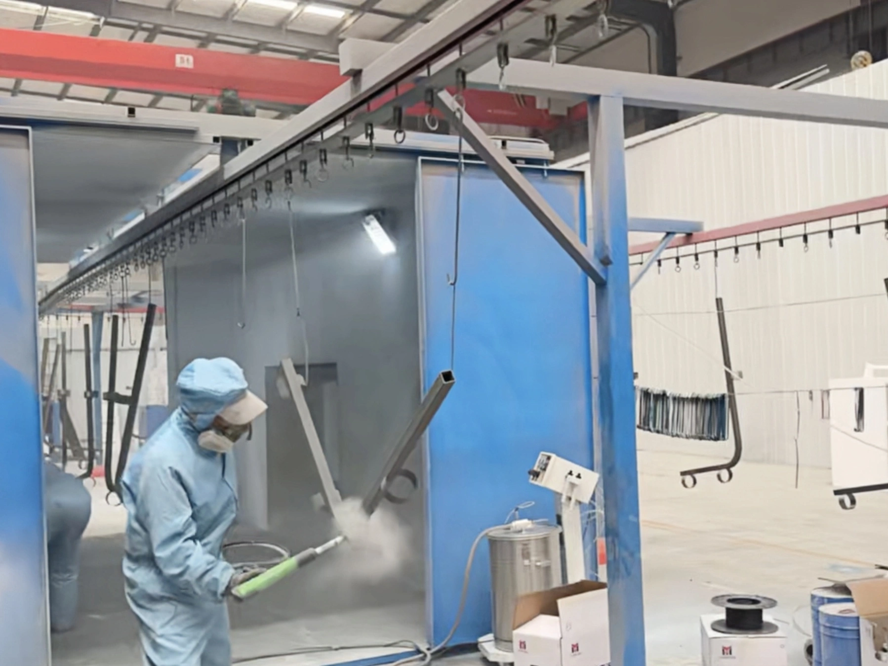 Spray-coating operation inside a blue industrial coating booth