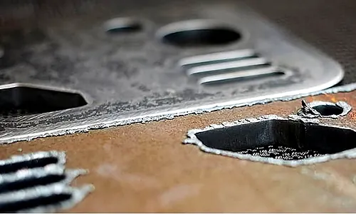 Cut metal parts showing rough residue around edges and openings