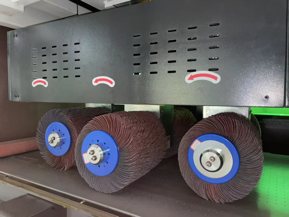 Close-up of abrasive brush rollers inside a sheet metal edge rounding machine