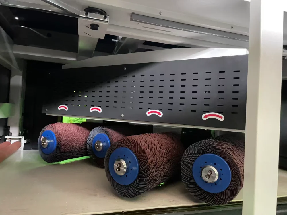 Row of abrasive brush rollers above the conveyor inside an edge rounding machine