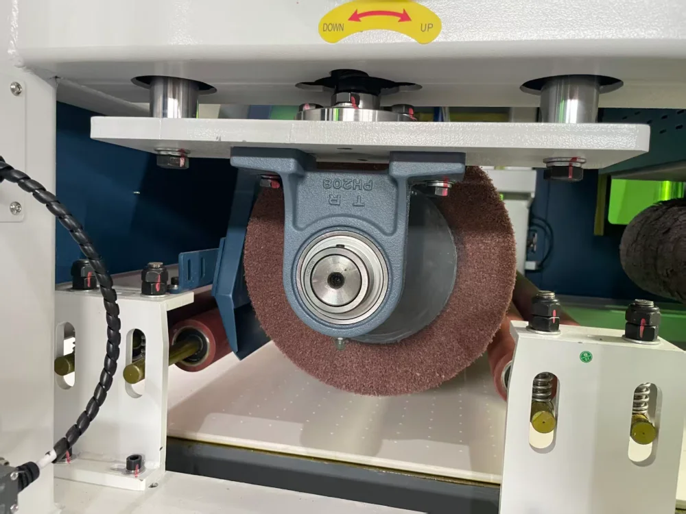 Close-up of a finishing roller and drive assembly inside a metal surface finishing machine