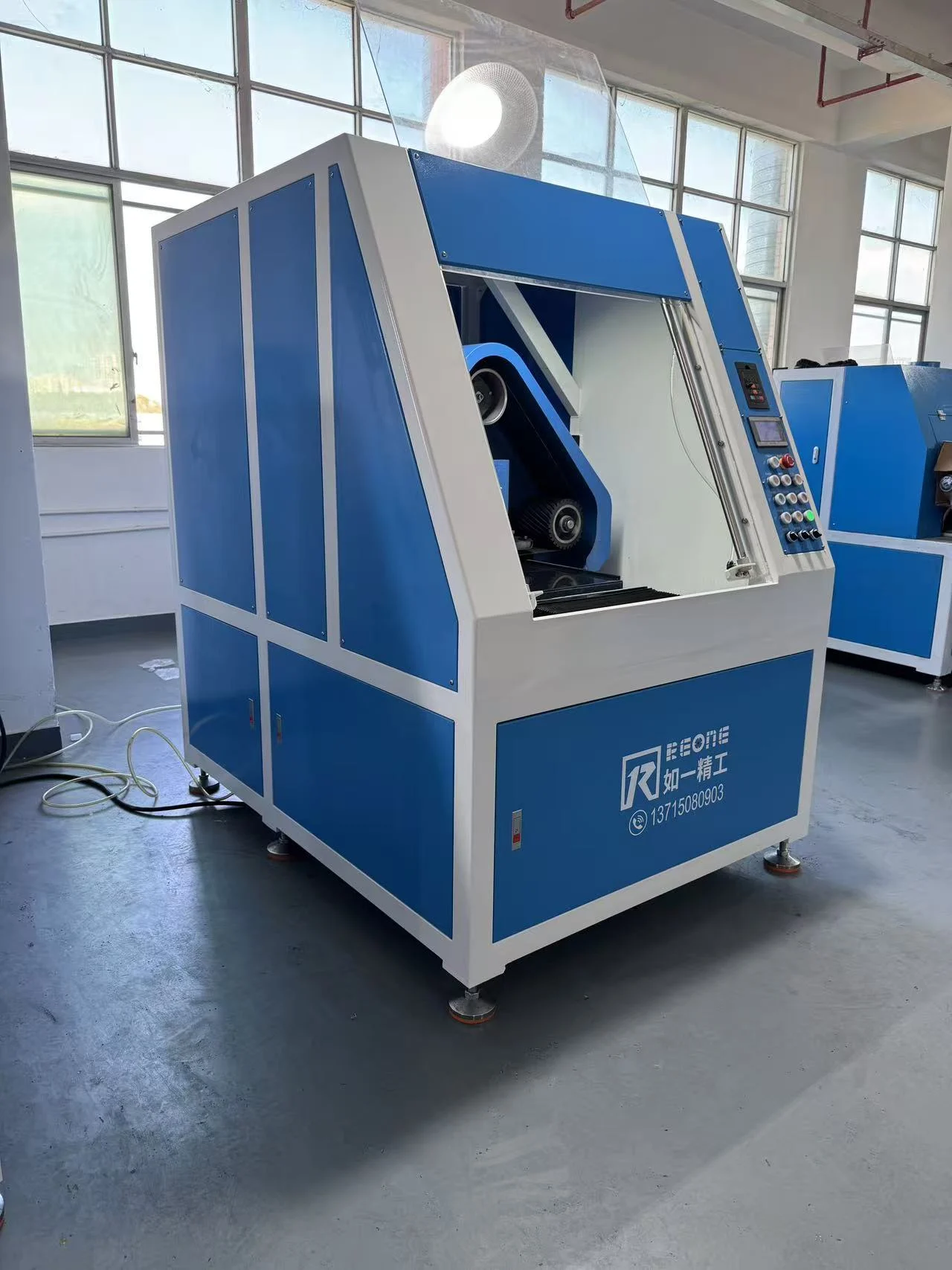 Wet polishing machine with a blue enclosure and front access opening in the workshop